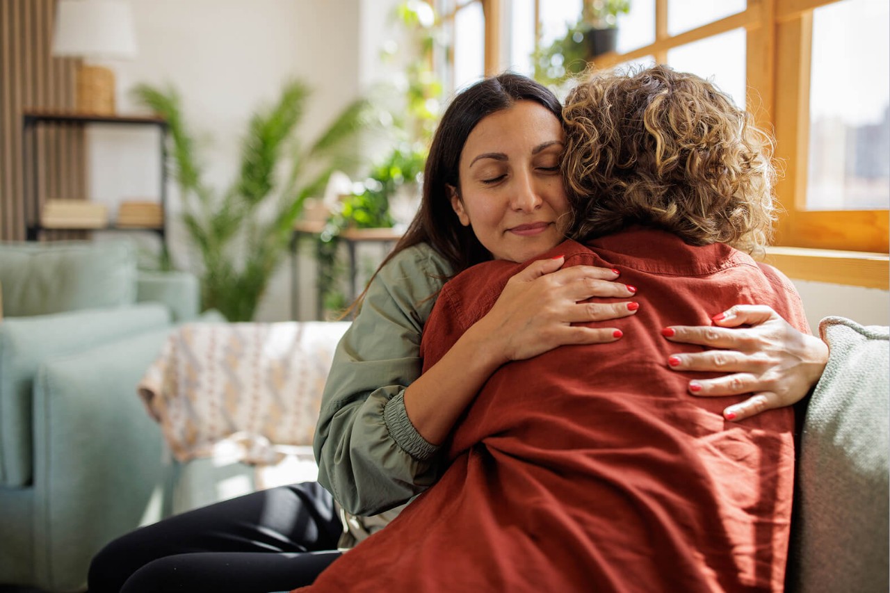 Two women hugging on a sofa
